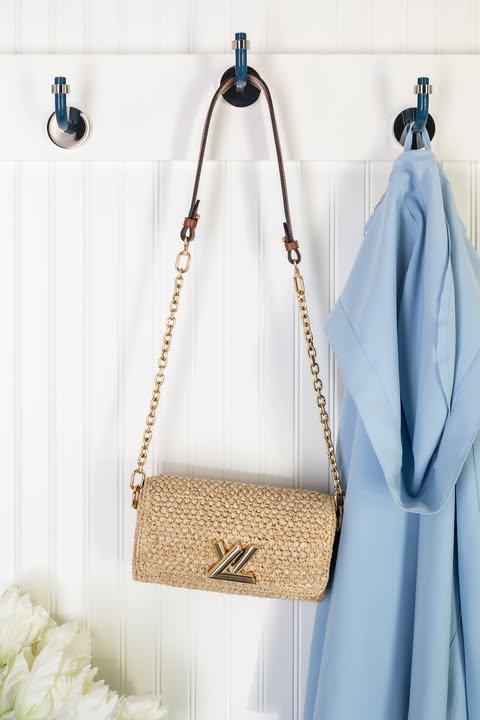 Light blue coat and purse hanging on a white wall with three slate blue and nickel snug hooks.